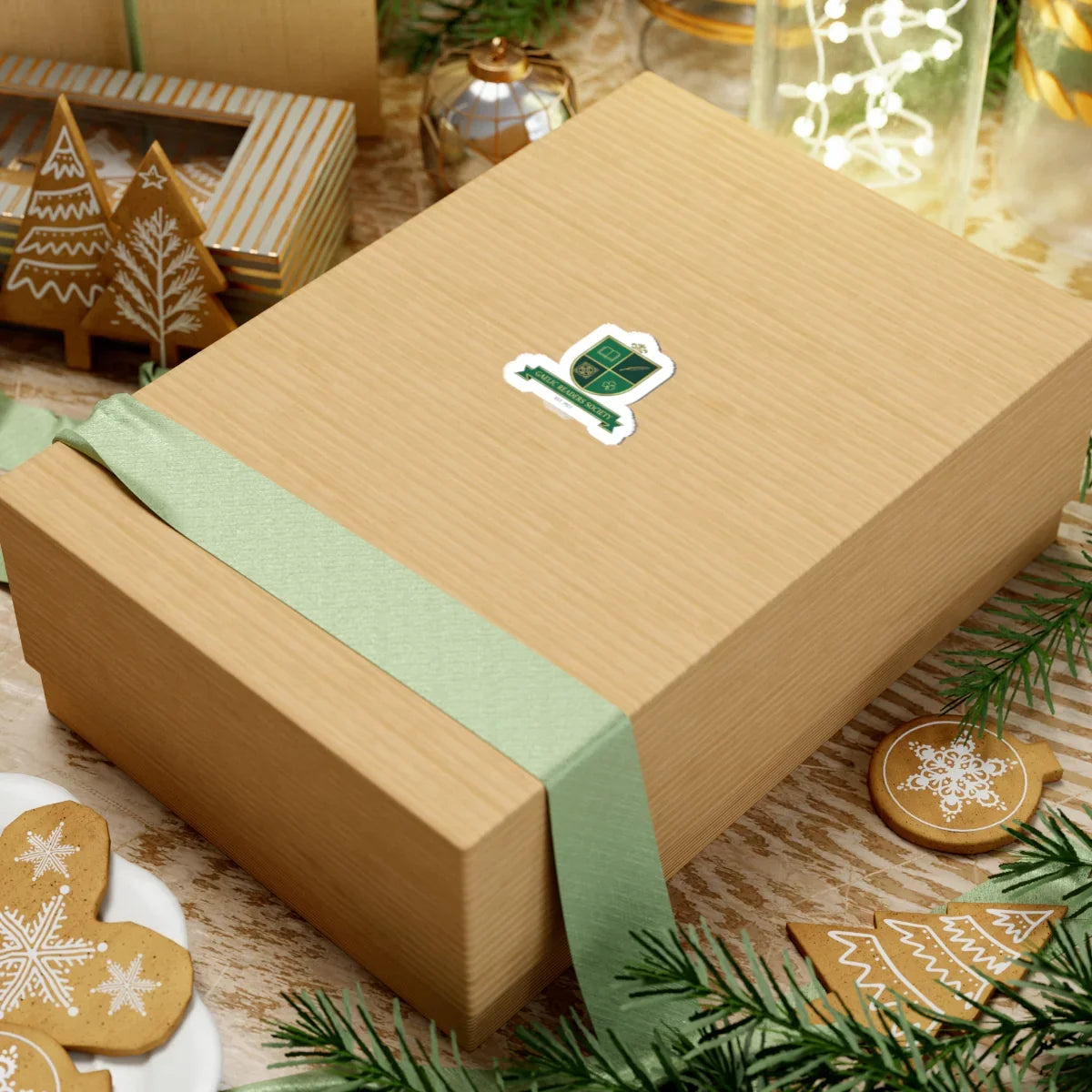 Gift box with green ribbon surrounded by Christmas cookies and holiday decorations